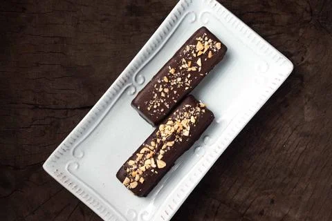 Two chocolate bars sit on a white plate Фото