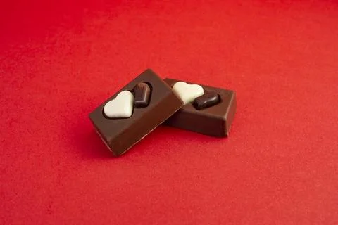 Two chocolate candy rectangles with hearts on red background  and copy spac.. Stock Photos