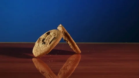 Two chocolate chip cookies fall and bounce on wood Stock Footage 327580910
