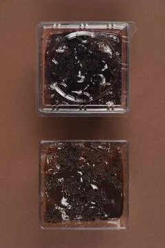 Two chocolate desserts in square plastic containers one covered Stock-Fotos