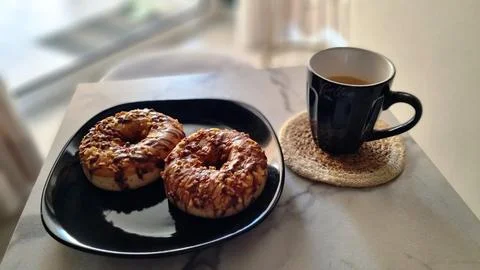 Two Chocolate Glazed Donuts with Chopped Nuts and Mug of Coffee 스톡 사진