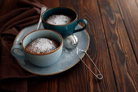 Two chocolate mug cake under sugar icing on dark wooden table. Easy homemad.. Stock Photos