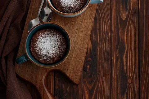 Two chocolate mug cake  under sugar icing on dark wooden table. Easy homema.. Stock Photos