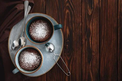 Two chocolate mug cake  under sugar icing on dark wooden table. Easy homema.. Stock Photos