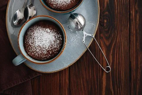 Two chocolate mug cake  under sugar icing on dark wooden table. Easy homema.. Stock Photos