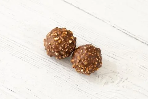 Two chocolate nut truffles rest on a white wooden surface Stock-Fotos