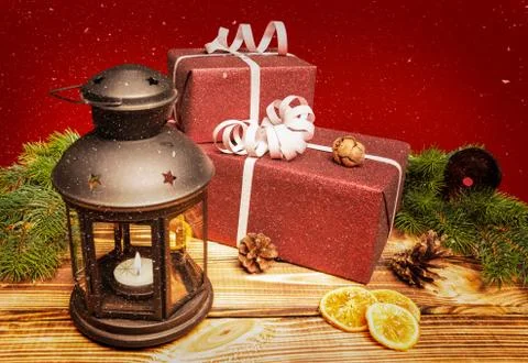 Two Christmas presents lie on a rustic wooden table with a lantern Stock Photos