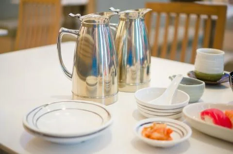 Two chrome shining tea pots with green tea in Japanese restaurant Stock Photos