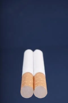 Two cigarettes on blue background Stock Photos