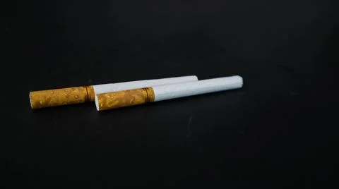 Two cigarettes placed on a black surface, highlighting the contrast between.. Foto stock