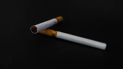 Two cigarettes placed on a black surface, highlighting the contrast between.. Stock Photos