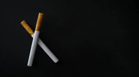 Two cigarettes placed on a black surface, highlighting the contrast between.. Stock Photos