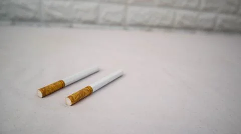 Two cigarettes placed on a white surface, showcasing their brown filters an.. Foto stock