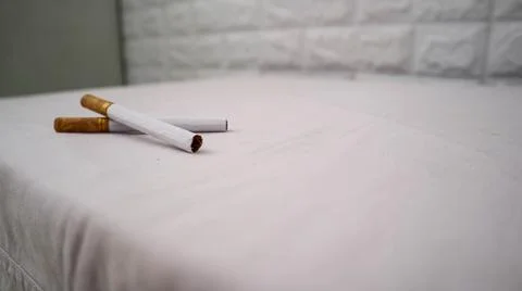 Two cigarettes placed on a white surface, showcasing their brown filters an.. Stock Photos