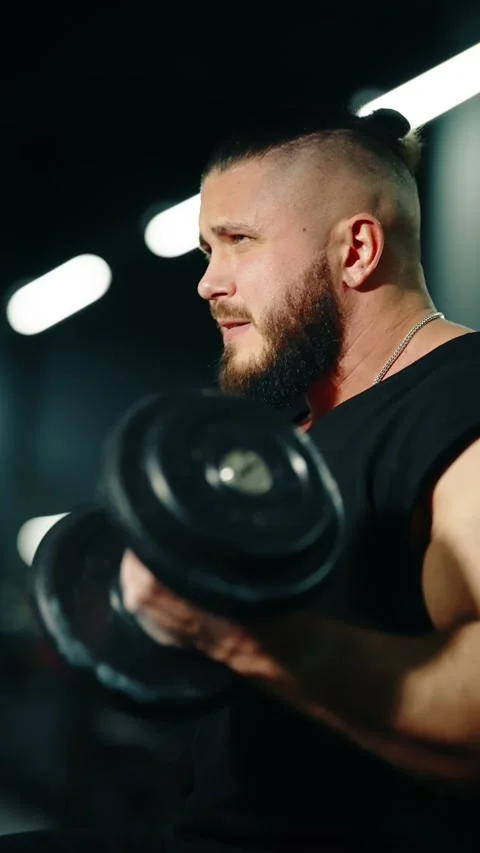 Two cinematic side-profile frames of a bearded, muscular man working out in a 库存影片 329556171
