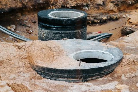 Two circular concrete access points are shown at a construction site with dirt Stock Photos