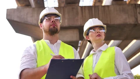 Two civil engineers, a young man and a young woman working on a project wearing Stock Footage 200791793