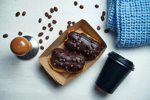 Two classic eclairs with chocolate icing and custard in a box on a white back Stock Photos