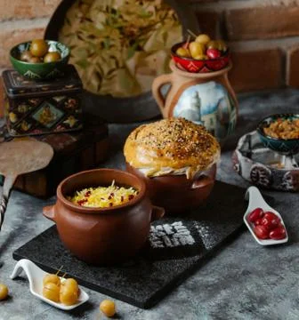 Two clay jars filled with rice and meat covered with dough crust Stock Photos