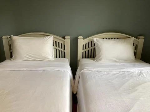 Two clean white beds with the light gray wall Stock Photos