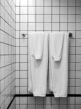 Two clean white towels folded hanging on a metal hanger bar white grid patter Stock Photos