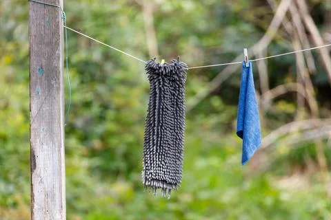 Two cleaning cloths hang drying on rustic clothesline outdoors Stockfoto's