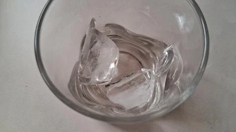 Two clear ice cubes inside a simple round glass tumbler Stock Photos