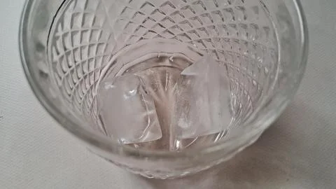 Two clear ice cubes inside a decorative patterned crystal glass tumbler Stock Photos