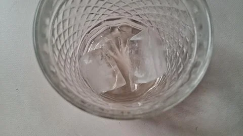 Two clear ice cubes inside a decorative textured crystal drinking glass Stock Photos