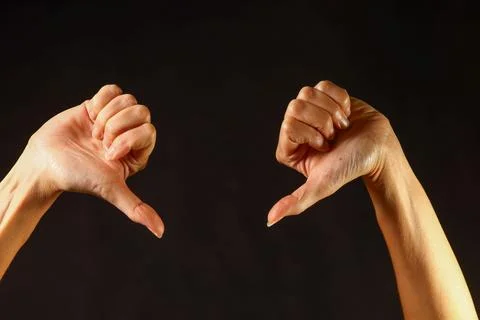 Two clenched hands with thumbs pointing downward, clear gesture of disapproval Stock Photos