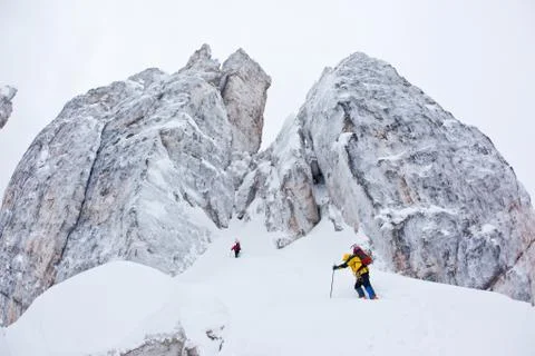 Two climbers approach to a winter steep face Stock Photos