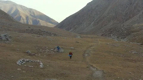 Two climbers with large backpacks and trekking poles approach a large rock Stock-Footage 259792700