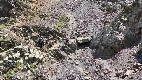 Two climbers with large backpacks descend from a high mountain 스톡 동영상 158095612
