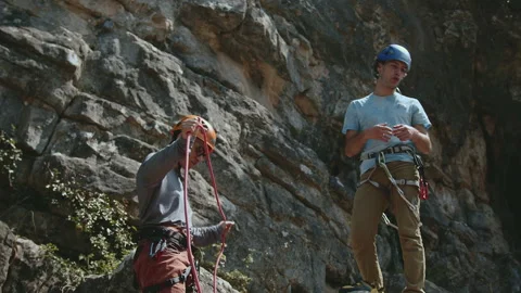 Two Climbers Preparing Gear for Rock Climb, Focused and Ready in Natural Setting Stock Footage 272626649