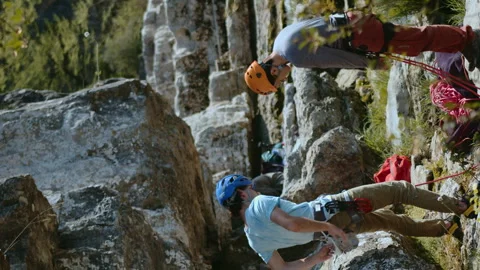 Two Climbers in Safety Gear Preparing for Ascent on Rocky Cliffside with Stock Footage 275855102