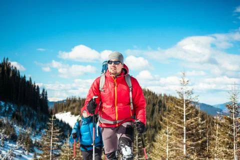Two climbers in snowshoes are in the mountains in the winter against fir tree Stock Photos