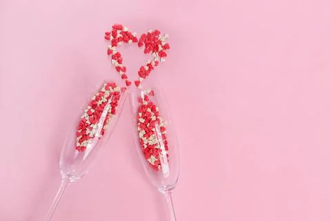Two clinking champagne glasses with small heart shaped sugar confetti Stock Photos