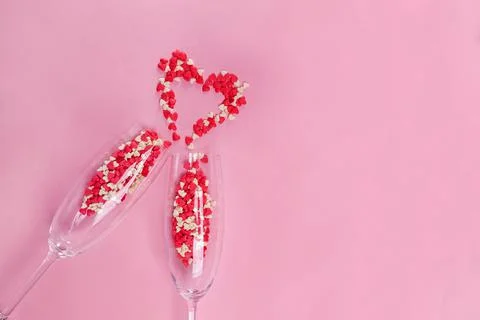 Two clinking champagne glasses with small heart shaped sugar confetti Stock Photos