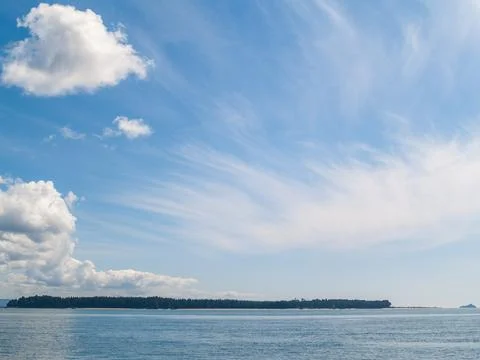 Two cloud formations over sea and low island background. 스톡 사진