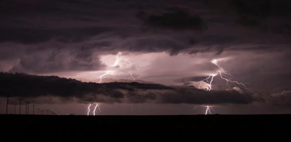 Two cloud-to-ground lightning bolts shoot through the low clouds of a supercell Stock Photos