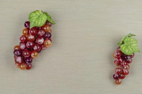 Two clusters of red grapes on a light brown background Stock Photos