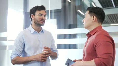 Two co-workers engaging in casual discussion with digital tablet and coffee  Stock Footage 299569611