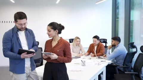 Two co-workers, man and woman engaged in discussion holding a digital tablet  Stock Footage 319070178