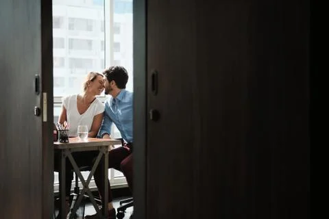 Two Co-Workers Sitting At Office Desk And Kissing Stock Photos