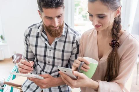 Two co-workers smiling while watching a video on the mobile in a Stock Photos