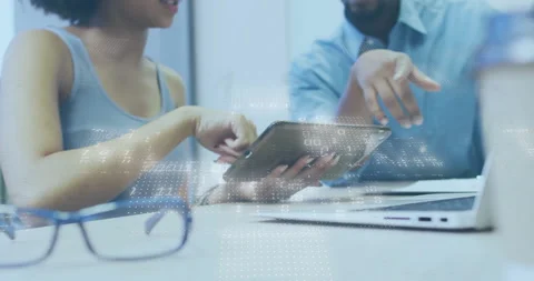 Two co-workers tapping tablet screen and comparing business data on laptop Stock Footage 309722598