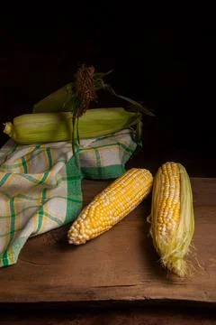 Two cobs sweet corn with green leaves on wooden background.. Stock Photos