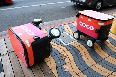 Two Coco Robotics food delivery robots with one robot lying on its side Foto stock
