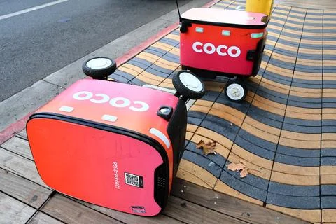 Two Coco Robotics food delivery robots with one robot lying on its side Foto stock