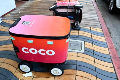 Two Coco Robotics food delivery robots with one robot lying on its side Foto stock